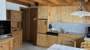 Eine Küche mit Holzausstattung, einem Geschirrspüler, einem Spülbecken und einem Tisch mit gestreifter Tischdecke.