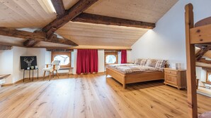 A bedroom with a wooden ceiling, a bed, a chair, a desk, and a window with curtains. - Wohnung von Schorsch, (Splügen), by Interhome (Splügen)
