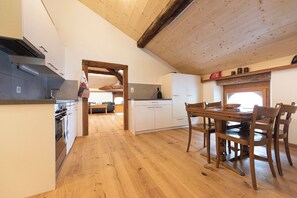 Eine Küche mit Holzboden, weißen Schränken und einem Essbereich mit Holzkohle.