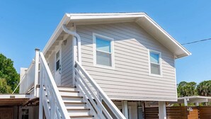 Ein zweistöckiges Haus mit weißer Fassade, einer Veranda und einer Treppe, die zum Eingang führt.
