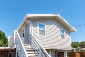 A two-story house with a white exterior, a front porch, and a staircase leading to the entrance. - Cozy Coastal Retreat Near Beach & Dining (Englewood)