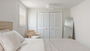Ein Schlafzimmer mit Bett, Stuhl, Kleiderschrank und Spiegel.