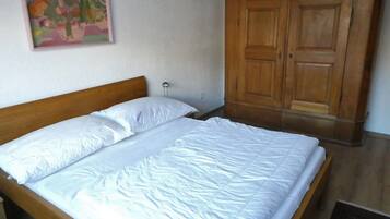 Ein Schlafzimmer mit einem hölzernen Bett, einem Kleiderschrank und einem Gemälde an der Wand.