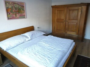 A bedroom with a wooden bed, a wardrobe, and a painting on the wall. - Viamalablick, (Thusis), by Interhome (Thusis)