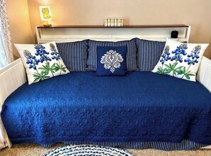 Ein Bett mit einer blauen Steude, gestreiften Kissen und einem Zierkissen.