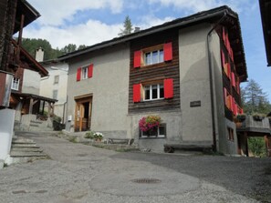 A traditional building with a stone facade, wooden shutters, and a bench in front. - Ferienwohnungen Jörihus A&B, (Medels), by Interhome (Splügen)