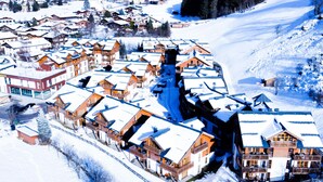 A snow-covered village with wooden buildings, including a hotel with balconies and a ski lift. - Apartment  by Interhome (Rauris)