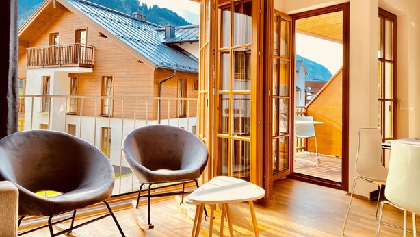 A modern room with a balcony, wooden flooring, and a view of a mountain. - Apartment  by Interhome (Rauris)