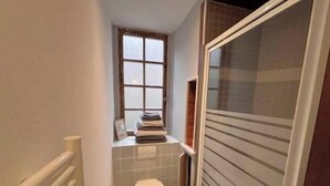 Een kleine badkamer met toilet, een raam en een handdoekhouder.