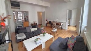 Een moderne woonkamer met een bank, salontafel en een eethoek met stoelen en een tafel.