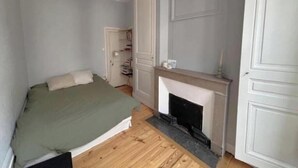 Een slaapkamer met een bed, een open haard en een kledingkast.