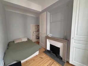 A bedroom with a bed, a fireplace, and a wardrobe. - Vieux Lyon - Historic charm, unique alcove & modern comfort rue Saint-Jean (Lyon)