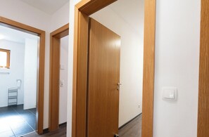 Ein Korridor mit Holztüren, die zu einem Badezimmer mit Handtuchhalter und Toilette führen.