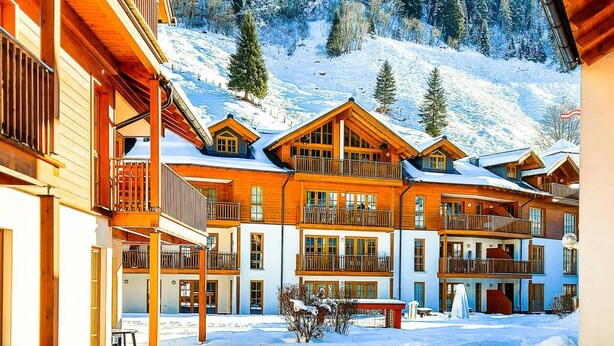 Un chalet enneigé doté de plusieurs balcons, avec une piste de ski en arrière-plan.