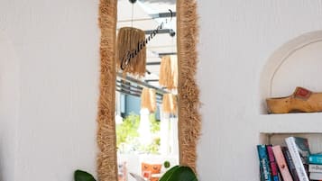 Un miroir avec un cadre rustique, une étagère remplie de livres et un luminaire suspendu.