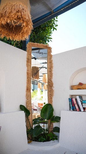 A mirror with a rustic frame, a shelf with books, and a hanging light fixture. - MENDOS GARDEN EXCLUSIVE (Muğla)