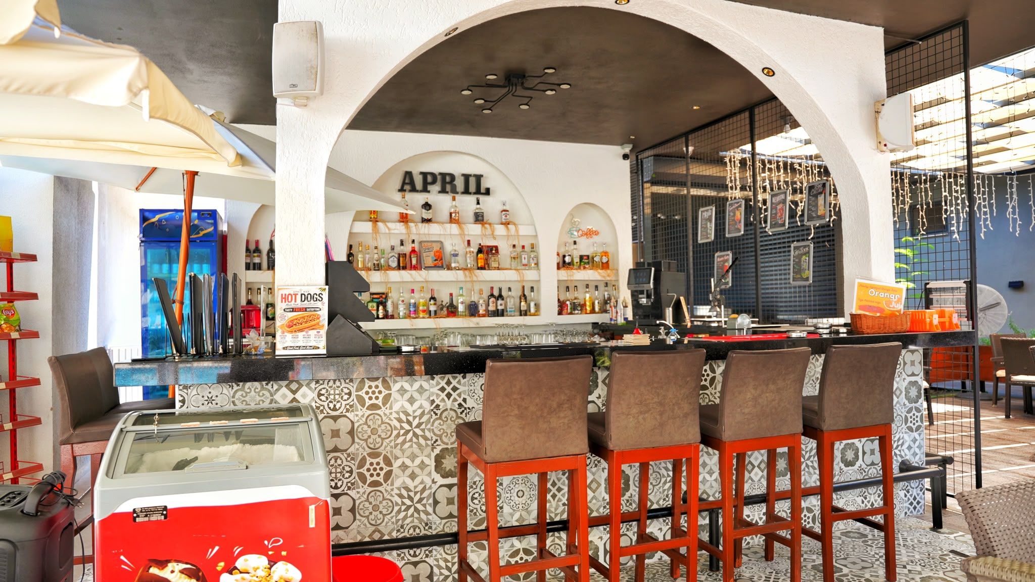 Zona de bar con un letrero que dice 'APRIL' y una barra con taburetes.