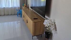 A room with a wooden ceiling, a large flat-screen TV, a wooden cabinet, a blue chair, and a potted orchid. - Fantastic 4-bedroom house in pleasant Gillitts for your getaway (Gillitts)