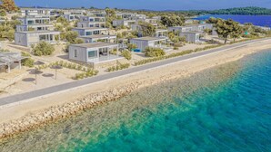 Ein Küstenresort mit modernen Blockhäusern, klarem türkisblauem Wasser und einem Sandstrand.
