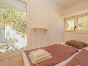 Una habitación con cama, ventana y estante de madera.