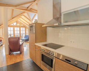 Une cuisine moderne avec des meubles en bois, un four encastré, un four à micro-ondes et une grande fenêtre.