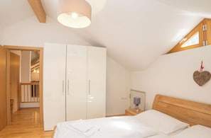 A bedroom with a large bed, a wardrobe, a bedside table with a lamp, and a heart-shaped decoration on the wall. - Schönblick - Daniela 7 by Interhome (Rauris)