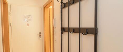 A hallway with a door, a coat rack, and a wall-mounted light switch.