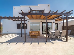 A covered outdoor seating area with a pergola, a sofa, and a dining table with chairs. - Casa OASIS DEL SOL, prívate villa in Playa Blanca by Interhome (Playa Blanca)
