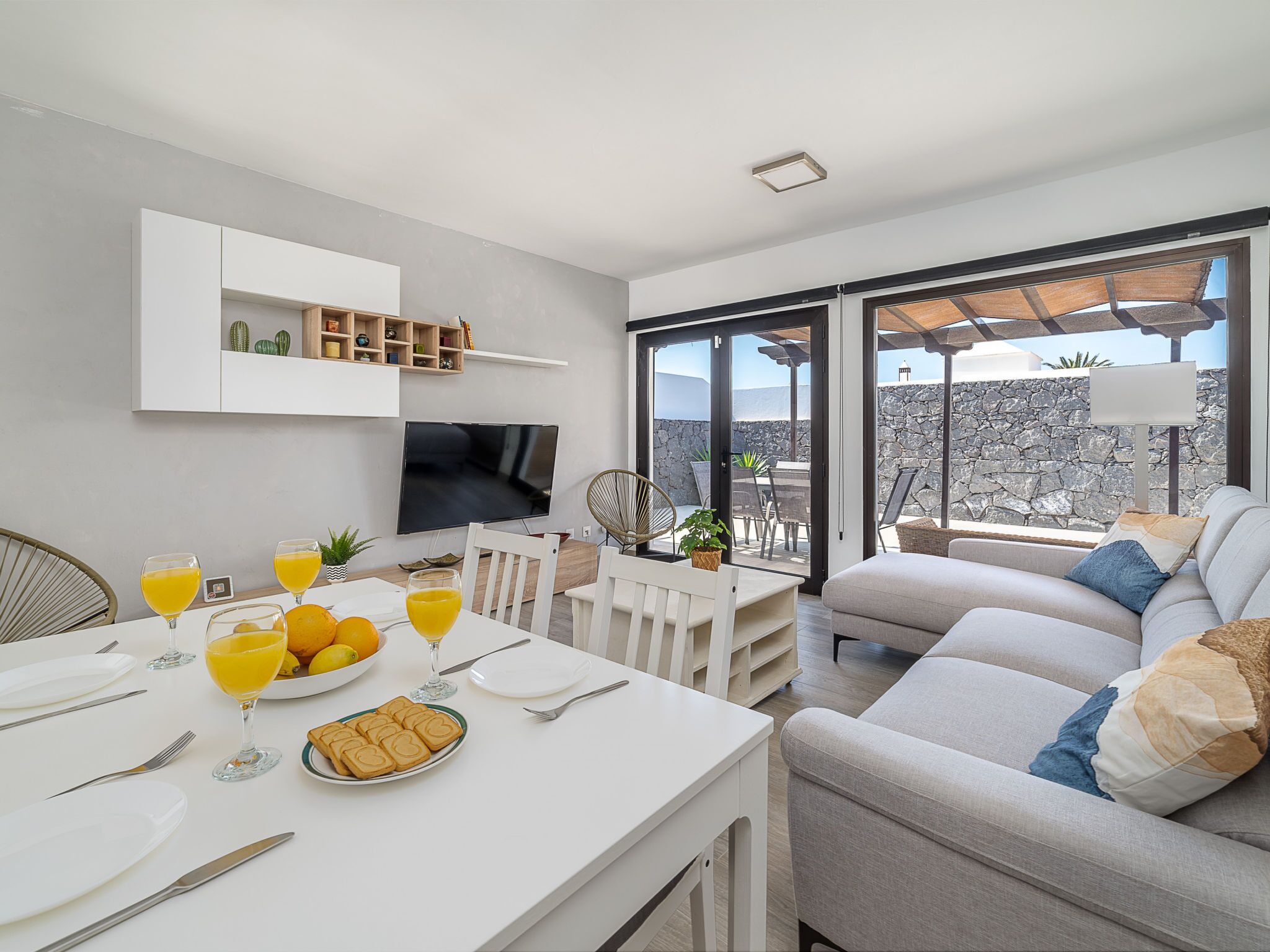 A modern living room with a dining area, a flat-screen TV, and a balcony with a view.