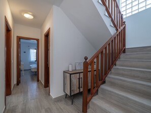 A modern interior with a wooden staircase, a hallway leading to a bathroom, and a small cabinet with a white appliance. - Casa OASIS DEL SOL, prívate villa in Playa Blanca by Interhome (Playa Blanca)