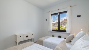 Een slaapkamer met twee bedden, een raam met gordijnen, een nachtkastje en een lamp.