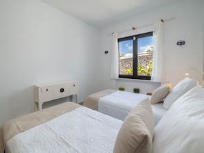 A bedroom with two beds, a window with curtains, a bedside table, and a lamp. - Casa OASIS DEL SOL, prívate villa in Playa Blanca by Interhome (Playa Blanca)