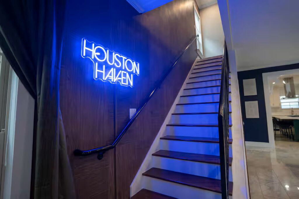 Una escalera con un letrero de neón que dice 'Houston Haalen' y un diseño interior moderno.