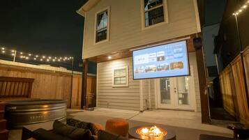 Una casa con porche mosquitero, chimenea y televisor mostrando un servicio de transmisión.