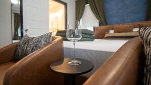 Et hotelværelse med en seng, et rundt bord med et glas vand og læderlænestole.