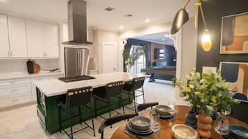 Una cocina moderna con una isla central, taburetes de bar y una mesa de comedor preparada para seis personas.