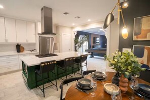 Una cocina moderna con una isla central, taburetes de bar y una mesa de comedor preparada para seis personas.