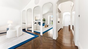 A spacious living area with a high ceiling, wooden flooring, and a blue accent rug. - GuestReady - Clérigos Luxury (Porto)