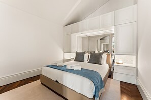 Ein Schlafzimmer mit einem Bett, einem Nachttisch, einem Spiegel und eingebauten Schränken.