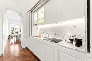 Eine moderne Küche mit weißen Schränken, einer Marmorarbeitsplatte und Blick auf die Stadt durch ein Fenster.