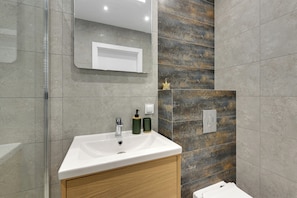 A modern bathroom with a white sink, wooden cabinet, and a mirror above it. - Plac Unii by Grand Apartments (Gdynia)