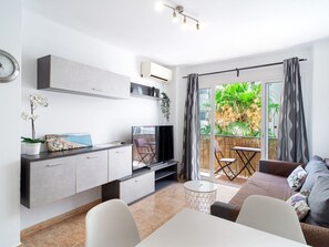 Una sala de estar moderna con una televisión de pantalla plana, una mesa de comedor y un sofá.