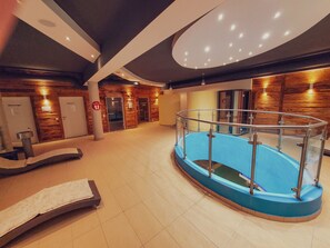 Ein Wellnessbereich mit Pool, Massageräumen und einer Rezeption.