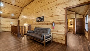 A wooden interior with a leather sofa, a fire extinguisher, and a framed picture on the wall. - Sleeps 20 | Private Indoor Pool, Theater, Arcade (Sevierville)