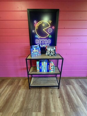 Uma prateleira com jogos de tabuleiro e um letreiro neon.