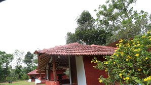 A rustic building with a red-tiled roof, a white exterior wall, and a porch area. - Sakleshpur Calm Stay (Alur)