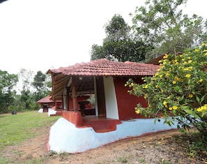 A rustic building with a red-tiled roof, a white exterior wall, and a porch area.