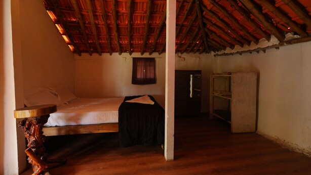 A room with a wooden ceiling, a bed, a small table, and a wardrobe. - Sakleshpur Calm Stay (Alur)