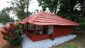 A small, red-roofed structure with a white base, surrounded by greenery. - Sakleshpur Calm Stay (Alur)