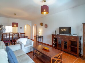 A living room with a sofa, a coffee table, a TV, and a wooden cabinet. - Apartment  by Interhome (Nerja)